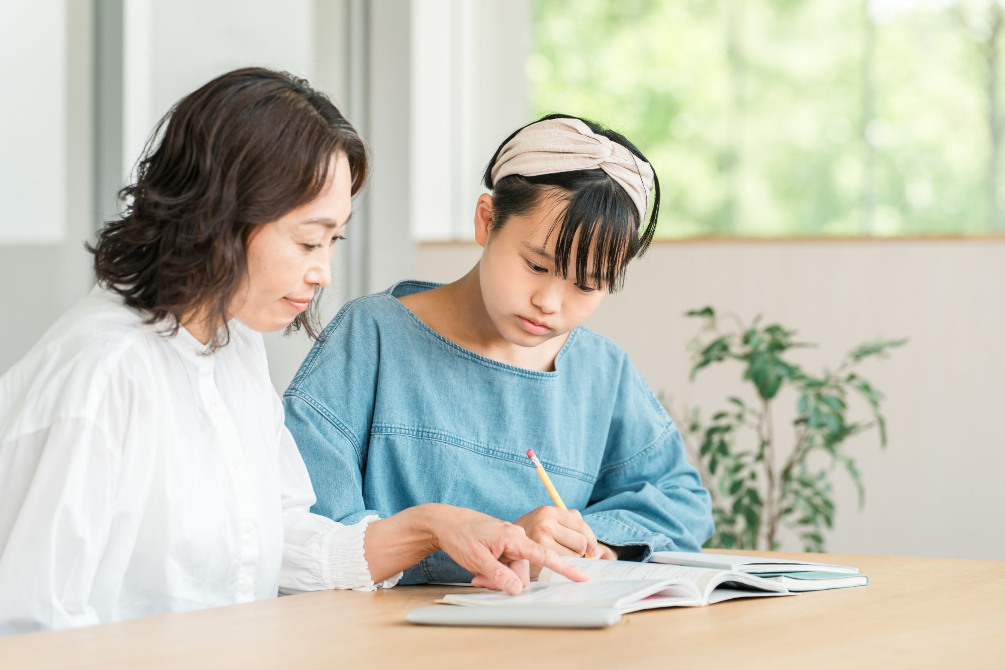 女性教師が教科書を開き小学生に指導