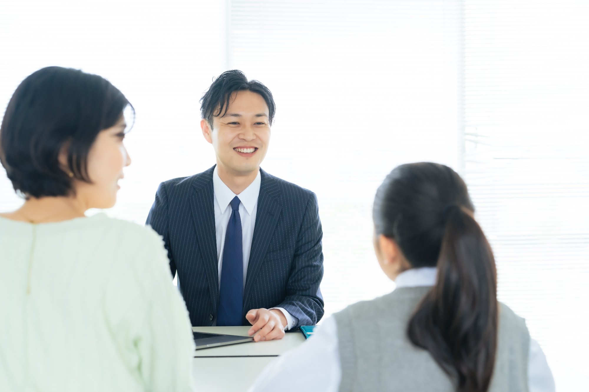 スーツの男性教師と母子の面談シーン